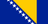 The flag of Bosnia and Herzegovina has a blue field, at the center of which is a large yellow hoist-side facing right-angled triangle that is based on the top edge and spans the height of the field. Adjacent to the hypotenuse of this triangle are nine adjoining five-pointed white stars with the top and bottom stars cut in half by the edges of the field.