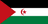 The flag of Western Sahara has three equal horizontal stripes of black, white, and green overlaid by a red triangle issuing from the hoist. Centered in the white band is a red fly-facing crescent surrounding a red five-pointed star.